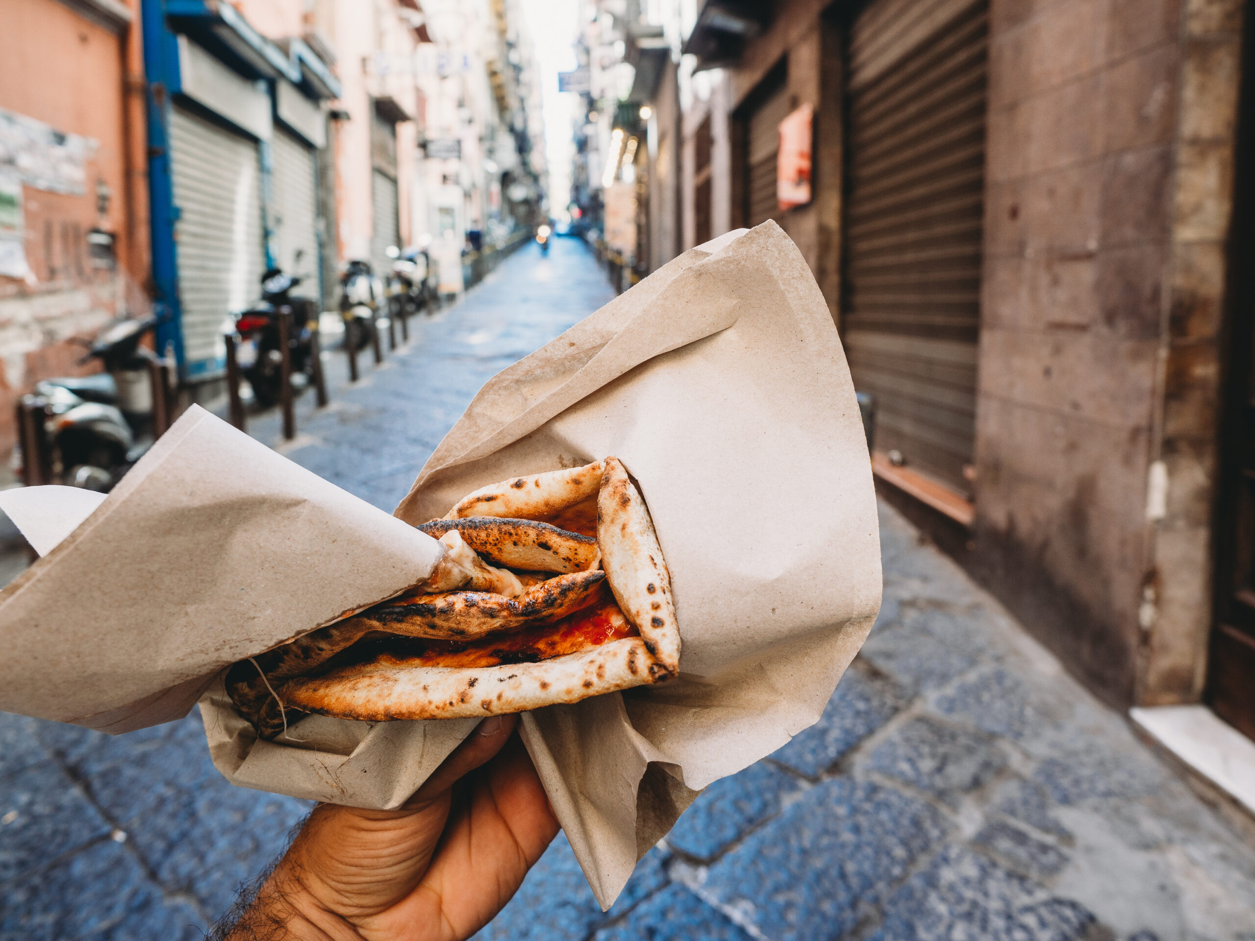 Pov view of a man eating a typical "Pizza a portafoglio" in Naples, Italy